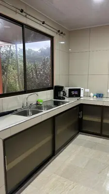 a kitchen with a sink and a large window at Hospedaje Arboleda in Quepos