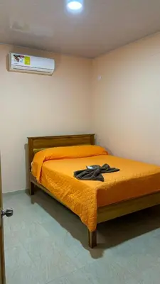 a bedroom with a bed with an orange blanket at Hospedaje Arboleda in Quepos