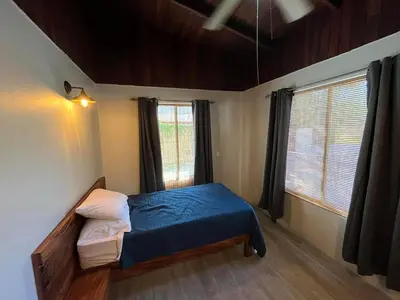 a small bedroom with a bed and two windows at 16 minutes from Tamarindo in Portegolpe
