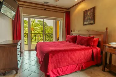 a bedroom with a red bed and a balcony at CR Luxury Veranda 7B 2 Bdrm in La Mona
