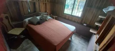 a small bedroom with a red bed and a chair at Cabaña Tiquisia in San Lorenzo