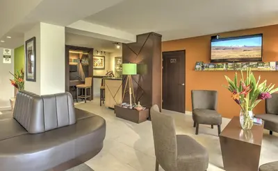 a living room with a couch and chairs and a tv at Hotel Residence Inn Suites Cristina in San José