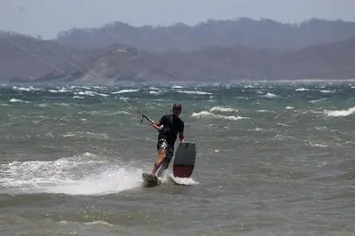 a man on a board in the water at Kite Bungalow Bahia Salinas in La Cruz