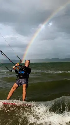 a man on a surfboard in the water with a rainbow at Kite Bungalow Bahia Salinas in La Cruz
