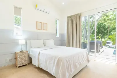 a white bedroom with a bed and a large window at Casa Blue Monkey - Playa Conchal in Brasilito