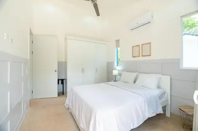 a white bedroom with a white bed and a window at Casa Blue Monkey - Playa Conchal in Brasilito