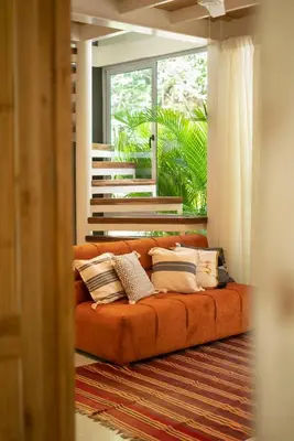 an orange couch in a living room with a window at Casa AguasPoolYoga deckwalk to Surf Point in Santa Teresa Beach