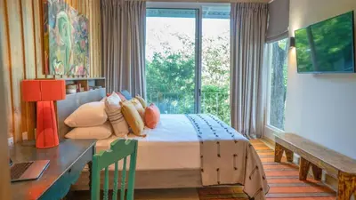a bedroom with a bed and a desk and a window at Casa AguasPoolYoga deckwalk to Surf Point in Santa Teresa Beach