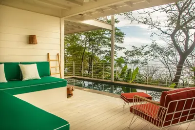 a screened in porch with a green couch and a chair at Casa Aliki, Luxury Beach Home with THE VIEW in Santa Teresa Beach