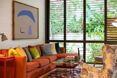 a living room with an orange couch and a table at Bamboo Bungalow in Santa Teresa Beach
