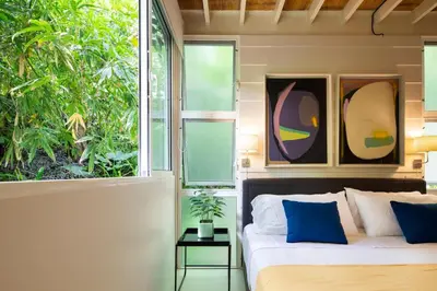 a bedroom with a bed with blue pillows and windows at Bamboo Bungalow in Santa Teresa Beach