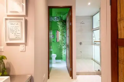 a bathroom with a toilet and a green wall at MAR A MAR Nest Bungalow - Pool WalkTo Beach in Santa Teresa Beach