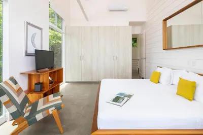 a bedroom with a bed and a tv and a chair at Casa AtrapasueñosEpic View Surfer's Paradise in Santa Teresa Beach