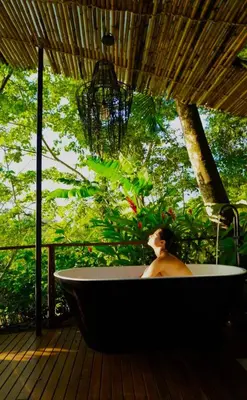 a man sitting in a bath tub on a deck at Casa RicaSunset ocean view pool fiber optic in Cóbano