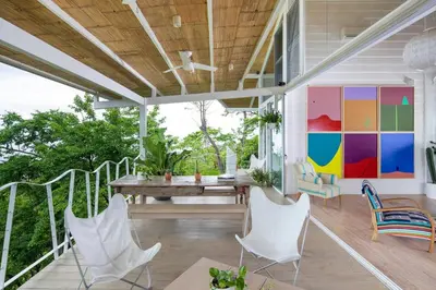 a porch with a table and chairs and a colorful wall at Casazul - Tropical escape ocean views in Santa Teresa Beach