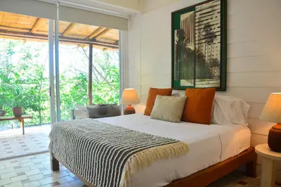 a bedroom with a bed in a room with windows at Tree NestNido 2- Ocean view- 5 min walk to beac in Santa Teresa Beach