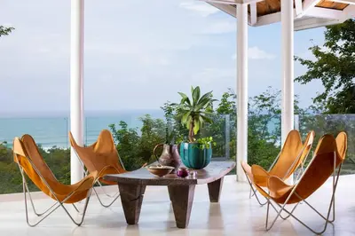 a dining room with a table and chairs and the ocean at Nido del Mar - Art-Filled Beach house in Santa Teresa