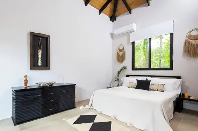 a bedroom with a black and white bed and a window at Villa Ayla - Santa Teresa Minutes from the beach in Carmen
