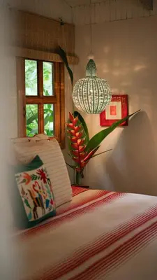 a bedroom with a bed with a lamp and a plant at Surf Casitas - High Tide Bungalow in Santa Teresa Beach