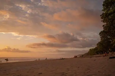 a group of people on the beach at sunset at Surf Casitas - High Tide Bungalow in Santa Teresa Beach