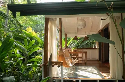 a patio with a table and a chair in a garden at Surf Casitas - Mid Tide Bungalow in Santa Teresa Beach