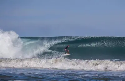 a man riding a wave on a surfboard in the ocean at Surf Casitas - Mid Tide Bungalow in Santa Teresa Beach
