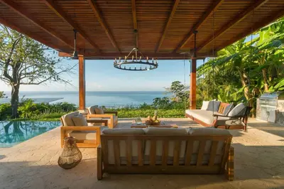 a patio with a couch and chairs and a chandelier at Casa Colibri - Stunning ocean view in Santa Teresa Beach