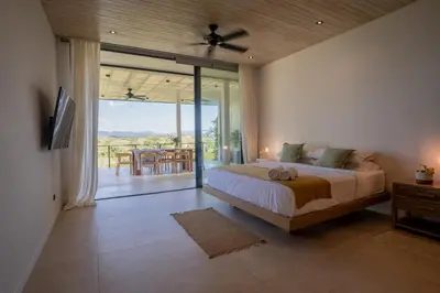a bedroom with a bed and a balcony with a table at Mahalo Villas in Playa hermosa