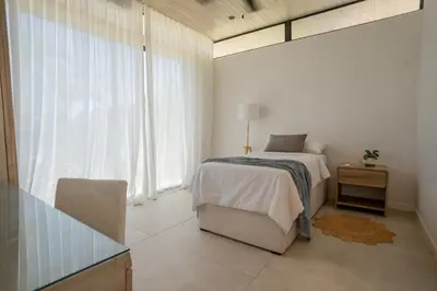 a white bedroom with a bed and a window at Mahalo Villas in Playa hermosa