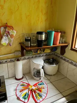 a kitchen with a counter with a shelf with pots and pans at Costa Rica Getaway in Jacó
