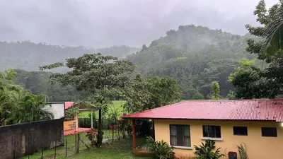 a house with a red roof in front of a mountain at Costa Rica Getaway in Jacó