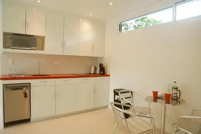 a kitchen with white cabinets and a table and a window at Villa Paradise Garden in Cabuya
