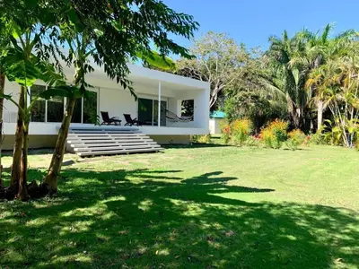 a white house with two chairs in a yard at Villa Paradise Garden in Cabuya