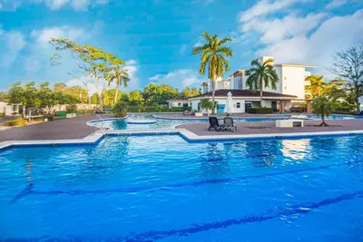 a large swimming pool in front of a house at 2 Bedroom Oceanfront Condo with Wi-Fi, AC and Pool in Bejuco