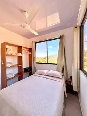 a bedroom with a bed and a large window at Apartamentos Aquí Me Quedo in Nandayure
