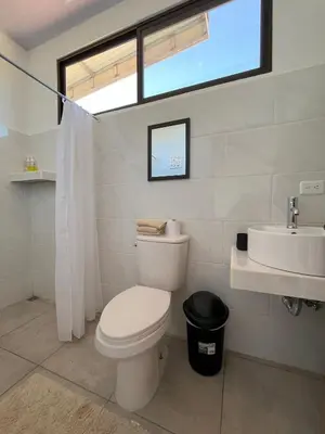 a bathroom with a toilet and a sink and a window at Apartamentos Aquí Me Quedo in Nandayure