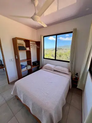 a bedroom with a bed and a large window at Apartamentos Aquí Me Quedo in Nandayure