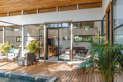 a house with sliding glass doors and a patio at Villa Primavera Santa Teresa Center- walking distance to the beach in Santa Teresa Beach