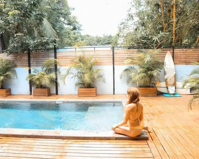 a woman in a bikini sitting next to a swimming pool at Villa Primavera Santa Teresa Center- walking distance to the beach in Santa Teresa Beach