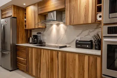 a kitchen with wooden cabinets and a stainless steel refrigerator at New! Ocean View, Jungle Surrounded, Walk to Beach & River in Uvita