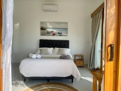 a bedroom with a large bed with white sheets at Casa Kairos CR, Playa Samara in Nicoya