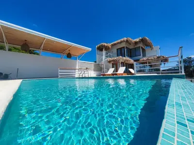 a villa with a swimming pool in front of a house at Casa Kairos CR, Playa Samara in Nicoya