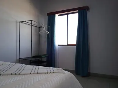 a bedroom with a bed and a window with blue curtains at Cabina Hermanas Valencia in Monteverde Costa Rica