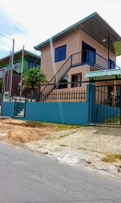 a house with a blue fence next to a street at Cabina Hermanas Valencia in Monteverde Costa Rica