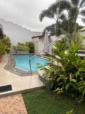 a swimming pool with an umbrella and some plants at Casa 8C Jaco Sol in Jacó