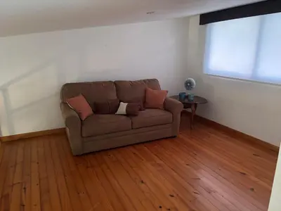 a brown couch in a living room with a wooden floor at Casa 8C Jaco Sol in Jacó