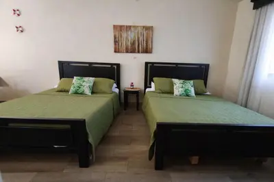 a bedroom with two beds with green sheets at Villa Jr 3, Piscina y Naturaleza, SJO Airport 80min in Tarcoles