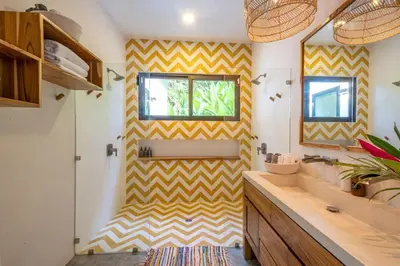 a bathroom with a yellow and white striped wall at Casita Pacífico Stunning Jungle Home in K-Section in Nicoya