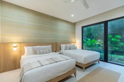 a bedroom with two beds and a large window at Pura Vida Peaceful Condo At Become Nosara in Nicoya