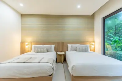 two beds in a room with a window at Pura Vida Peaceful Condo At Become Nosara in Nicoya